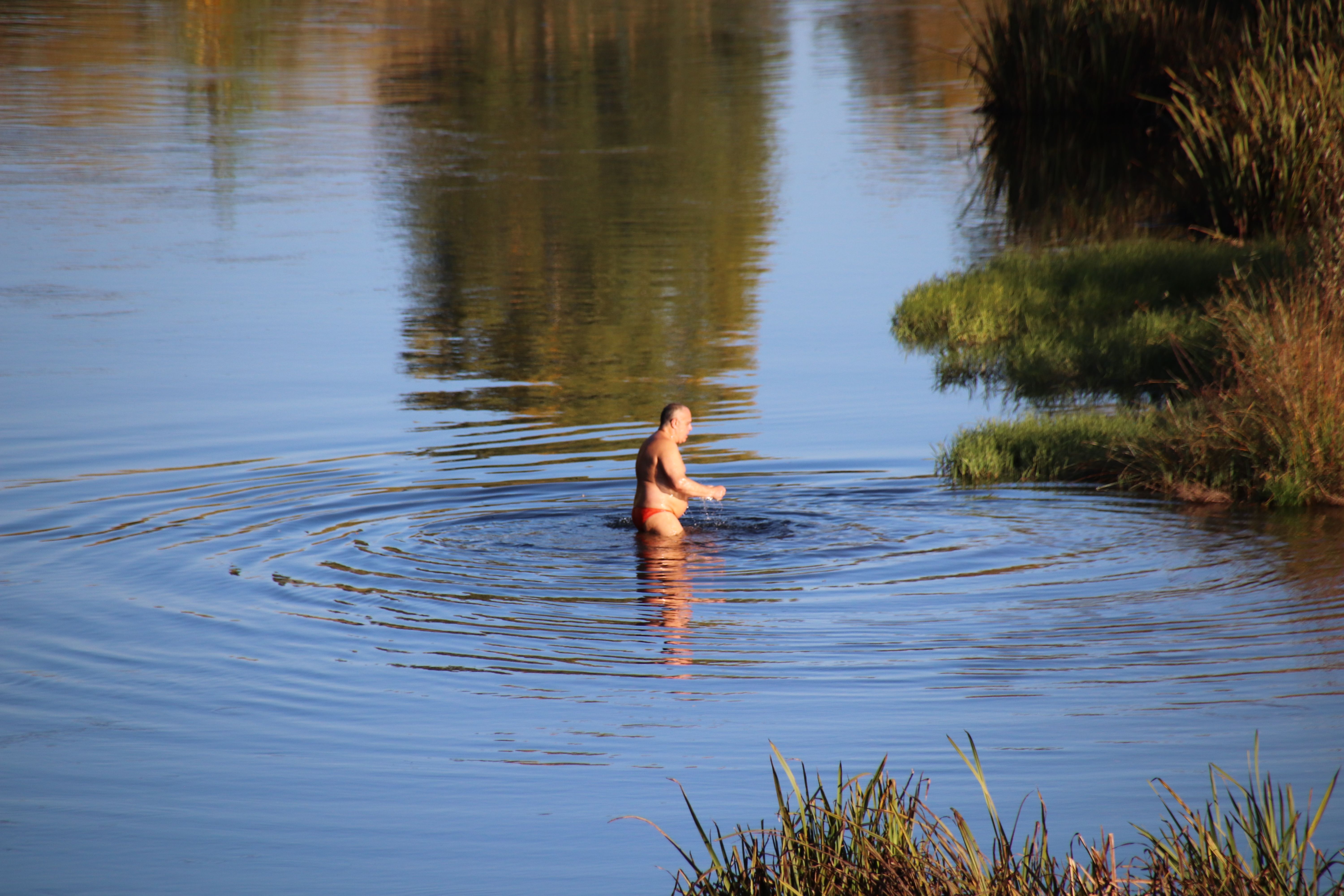 Señor bañándose en el río en pleno otoño