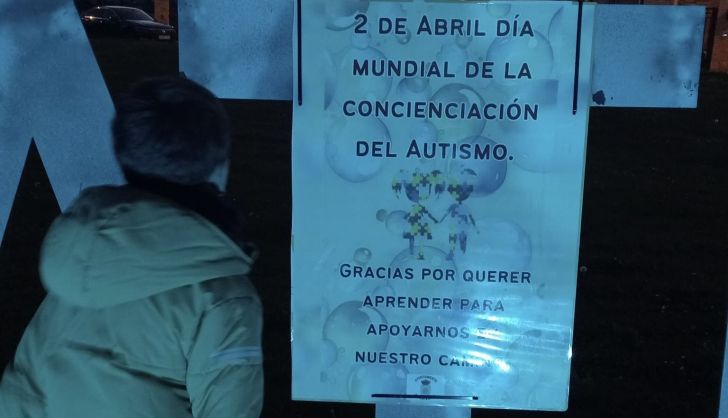 Asier frente a uno de los carteles que luce Aldeatejada por el Día Mundial del Autismo