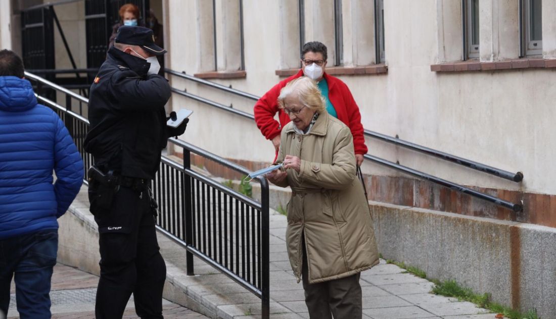 El agente de Policía Nacional entrega la mascarilla a la mujer